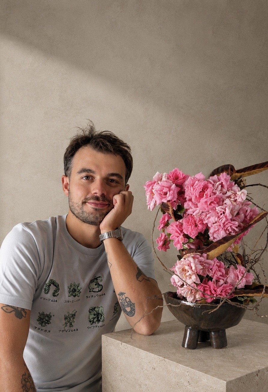 Federico Gasparrini accanto a una composizione ikebana di azalee rosa in una coppa nera